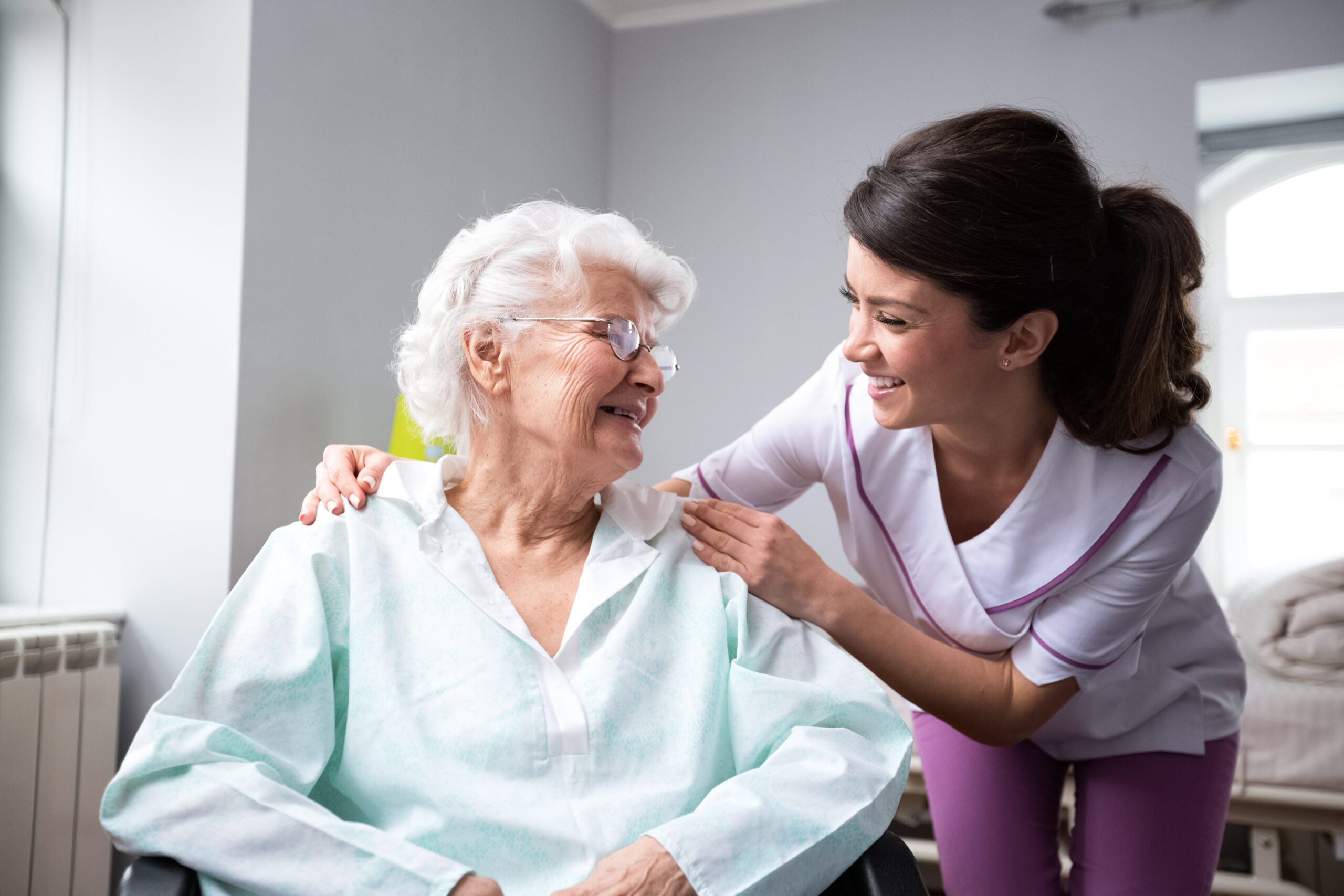 Satisfied and happy senior woman patient with nurse at nursing home